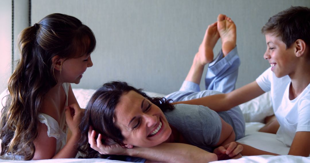 Mother Laughing with Children on Bed in Cozy Home - Free Images, Stock Photos and Pictures on Pikwizard.com