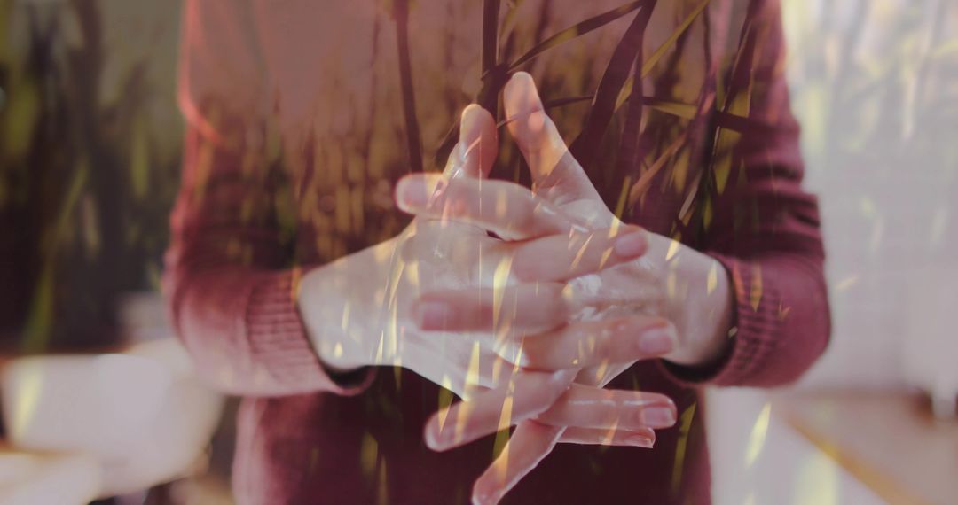 Double Exposure Hands Clasped in Maroon Sweater with Grass Overlay Conveying Introspection