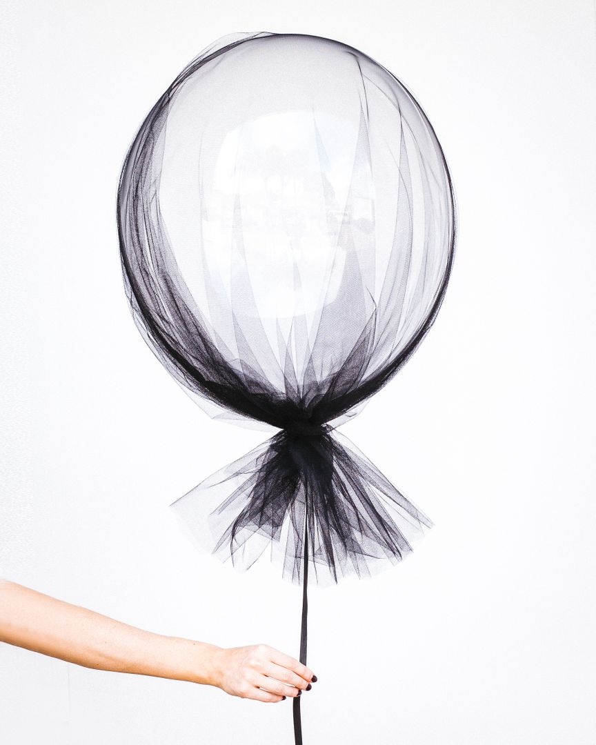 Hand Holding Black Tulle Covered Balloon Against White Background - Free Images, Stock Photos and Pictures on Pikwizard.com
