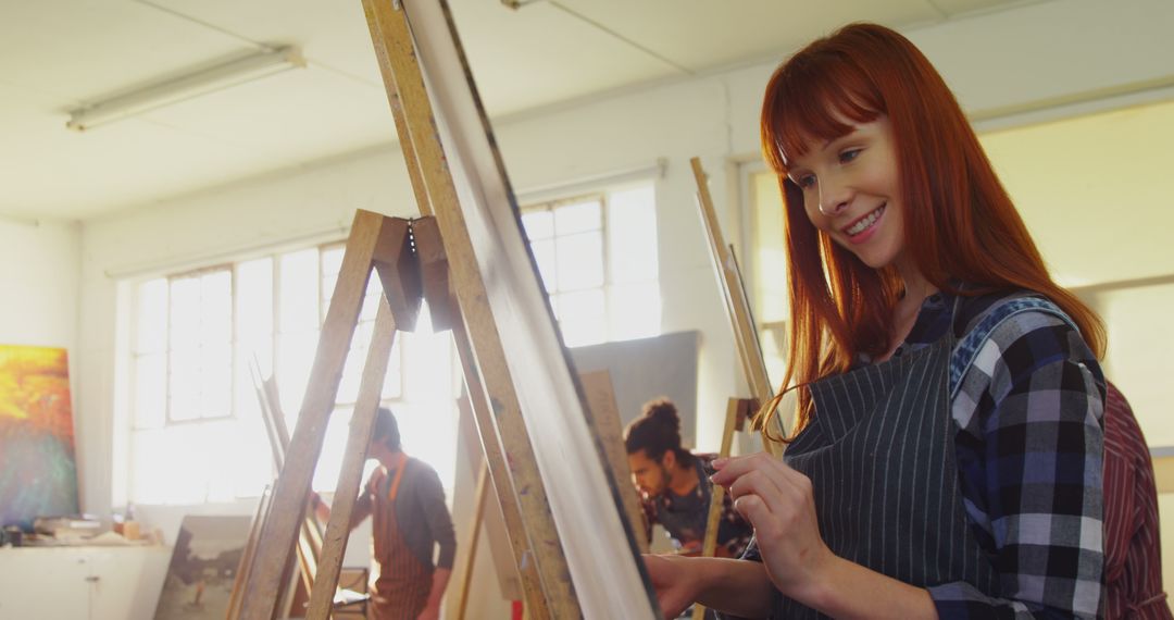 Young Female Artist Smiling While Painting in Studio - Free Images, Stock Photos and Pictures on Pikwizard.com