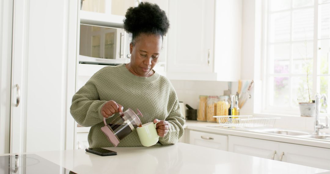 Senior Woman Pouring Coffee in Modern Kitchen - Free Images, Stock Photos and Pictures on Pikwizard.com