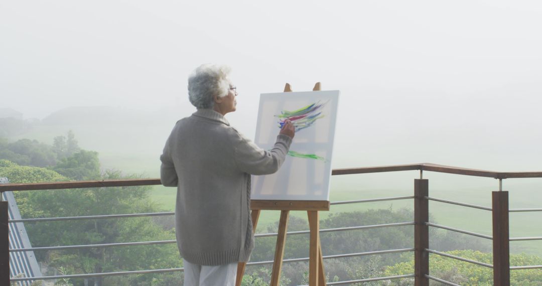 Senior Woman Painting on Outdoor Terrace in Scenic Foggy Morning - Free Images, Stock Photos and Pictures on Pikwizard.com