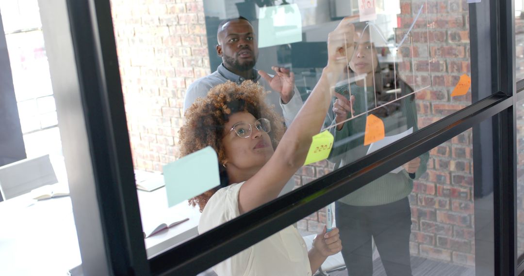 Diverse Team Brainstorming on Glass Wall with Sticky Notes - Free Images, Stock Photos and Pictures on Pikwizard.com