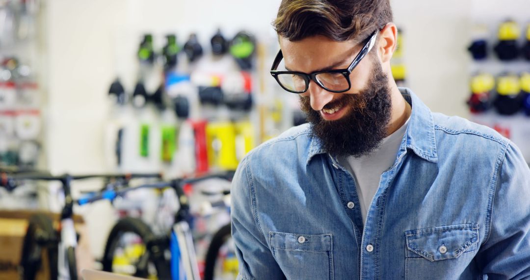 Cheerful Young Man Working in Bicycle Store Smiling Below Beard - Free Images, Stock Photos and Pictures on Pikwizard.com