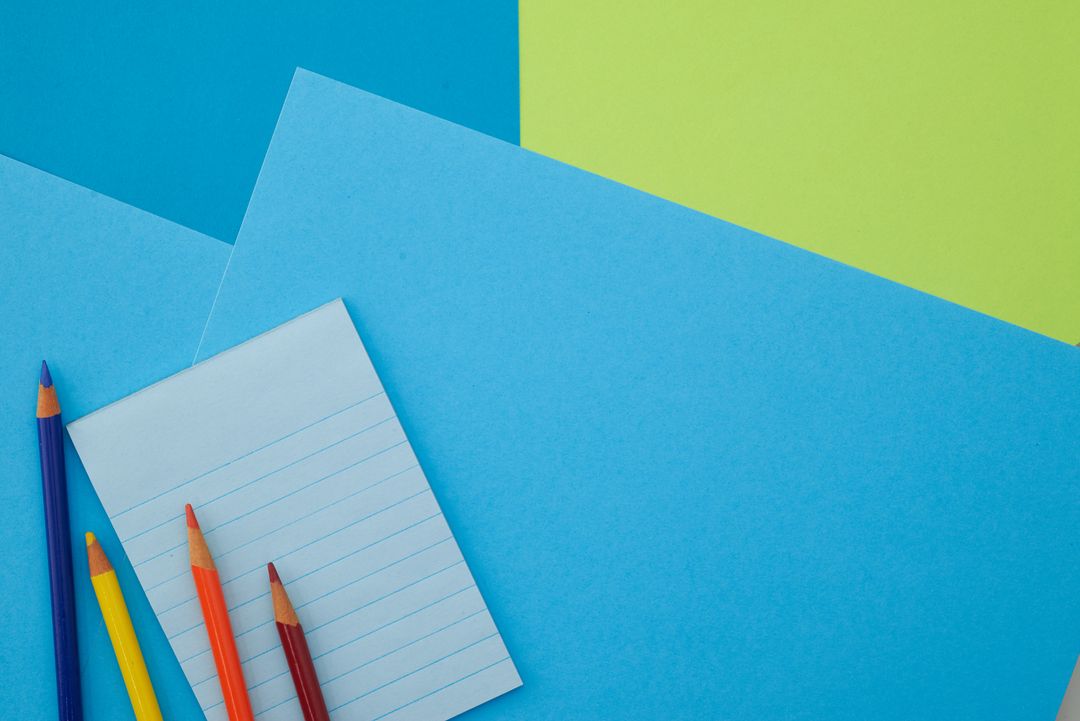 Bright blue stationery flat lay featuring lined notepad and colored pencils on paper