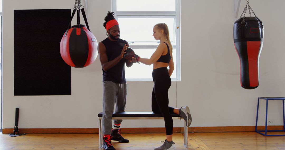 Personal Trainer Helping Female Client with Boxing Gloves in Gym