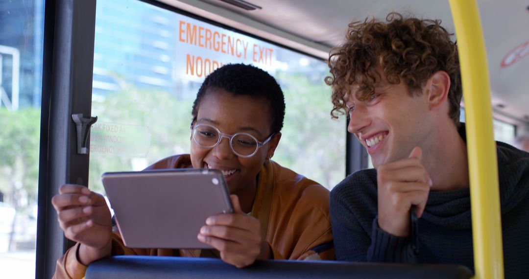 Two Multiracial Friends Sharing a Tablet on Bus Trip - Free Images, Stock Photos and Pictures on Pikwizard.com