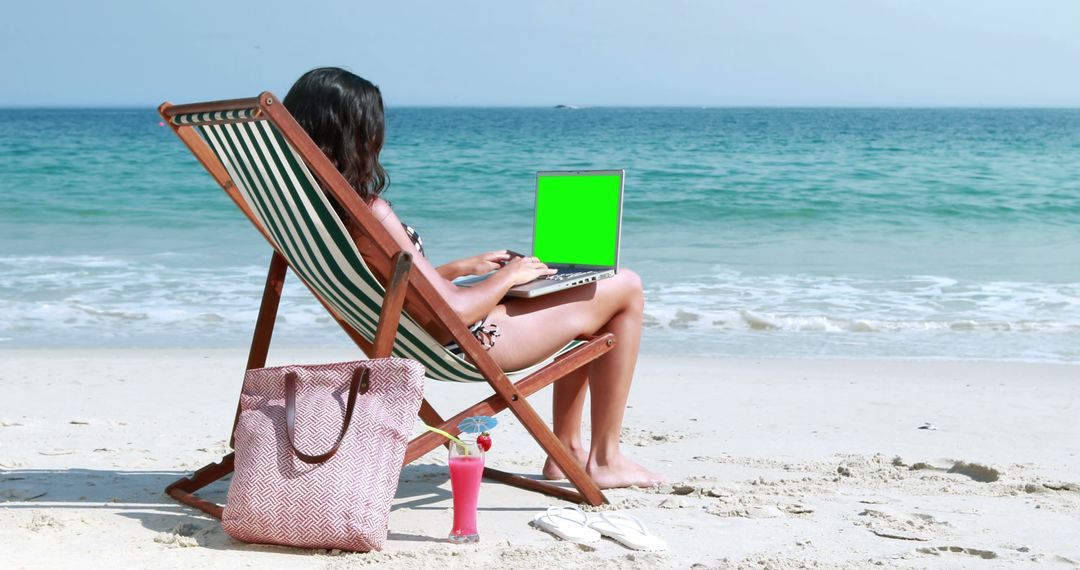 A young woman sits on a beach chair working on a laptop with a green screen, with copy space - Free Images, Stock Photos and Pictures on Pikwizard.com