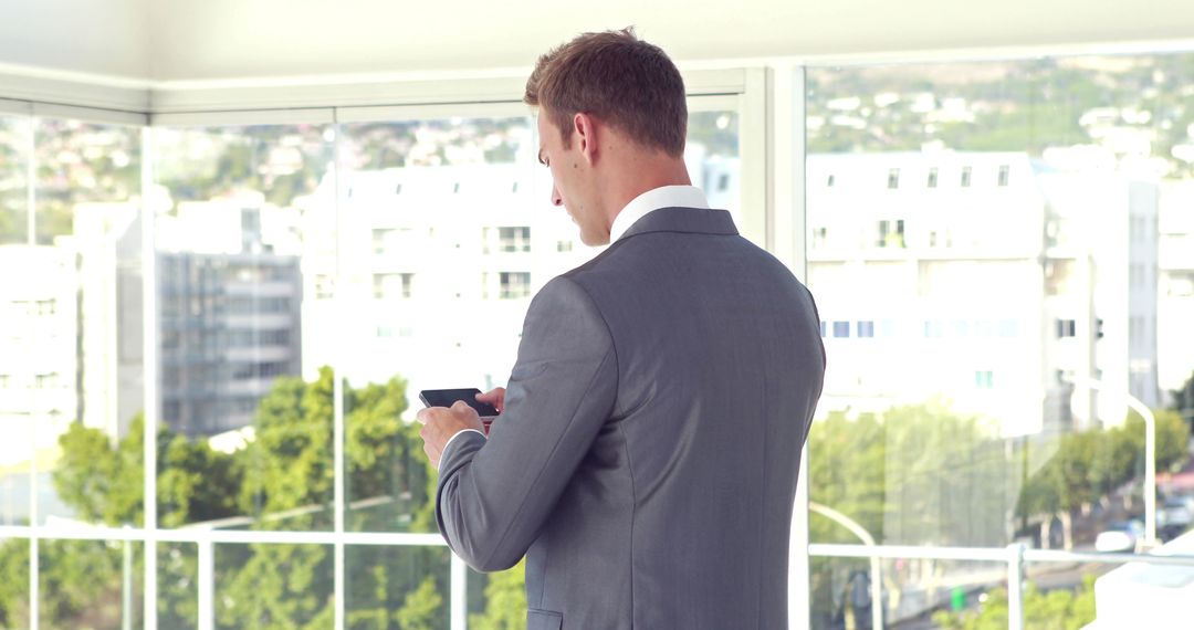 Businessman Texting on Smartphone in Bright Office - Free Images, Stock Photos and Pictures on Pikwizard.com