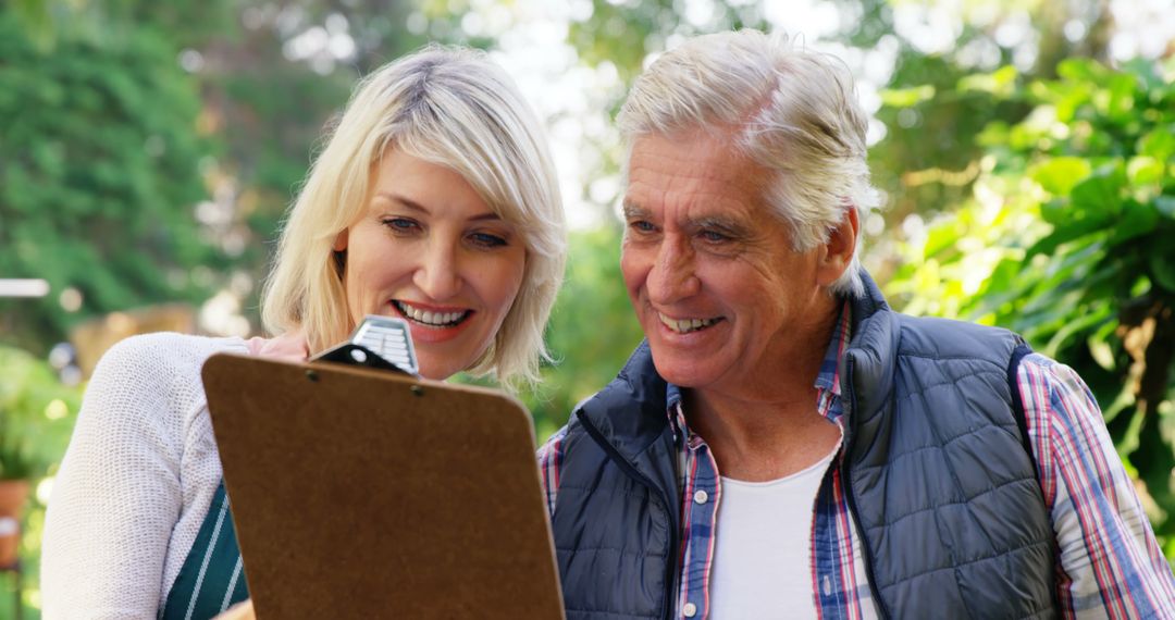 Senior Man and Woman Smiling and Reviewing Clipboard Outdoors - Free Images, Stock Photos and Pictures on Pikwizard.com