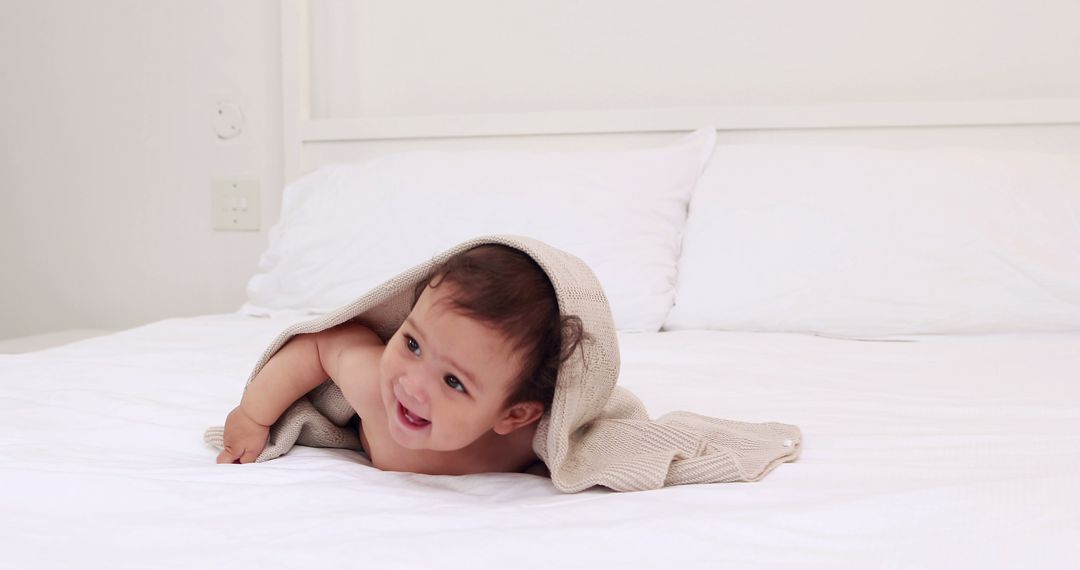 Adorable Baby Smiling While Lying on Bed Wrapped in Blanket - Free Images, Stock Photos and Pictures on Pikwizard.com