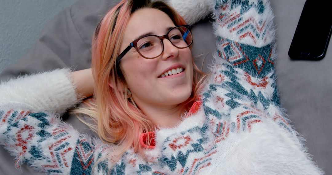 Young woman relaxing on couch wearing patterned sweater - Free Images, Stock Photos and Pictures on Pikwizard.com