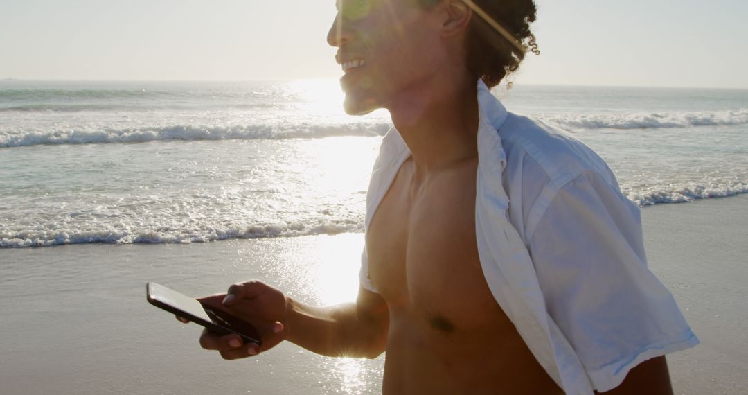 Carefree Young Man Walking on Beach Using Smartphone - Free Images, Stock Photos and Pictures on Pikwizard.com