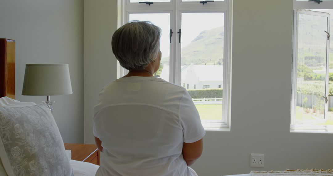 Elderly Woman Looking Out Window in Peaceful Room - Free Images, Stock Photos and Pictures on Pikwizard.com