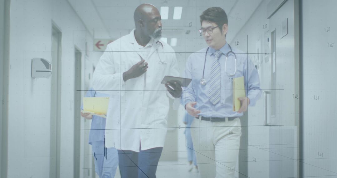 Doctors walking and reviewing tablet while carrying patient files in hospital corridor