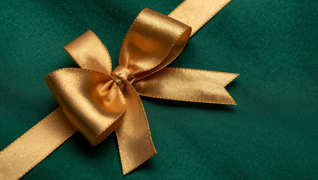 Shimmering Gold Satin Bow Resting on Emerald Velvet with Diagonal Ribbon