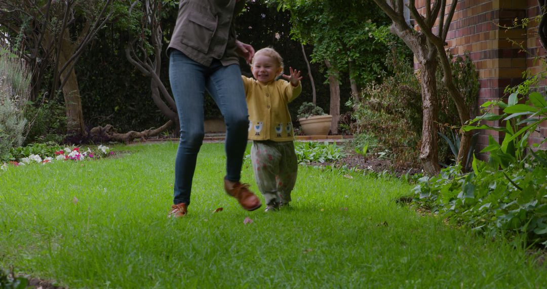 Happy child in yellow jacket running in garden with adult - Free Images, Stock Photos and Pictures on Pikwizard.com