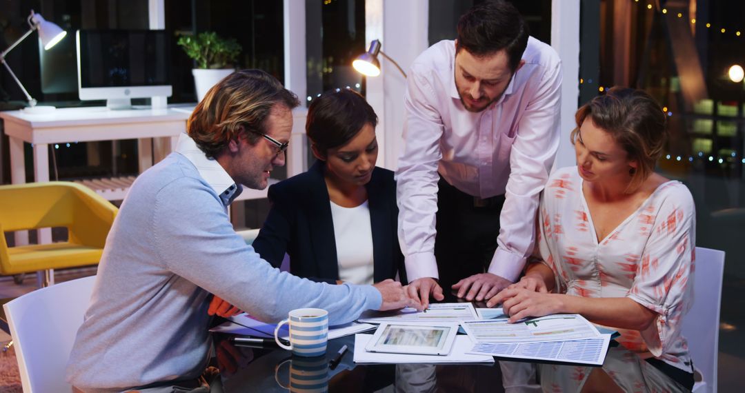 Dedicated Team Working Late in Modern Office Collaboratively Analyzing Documents