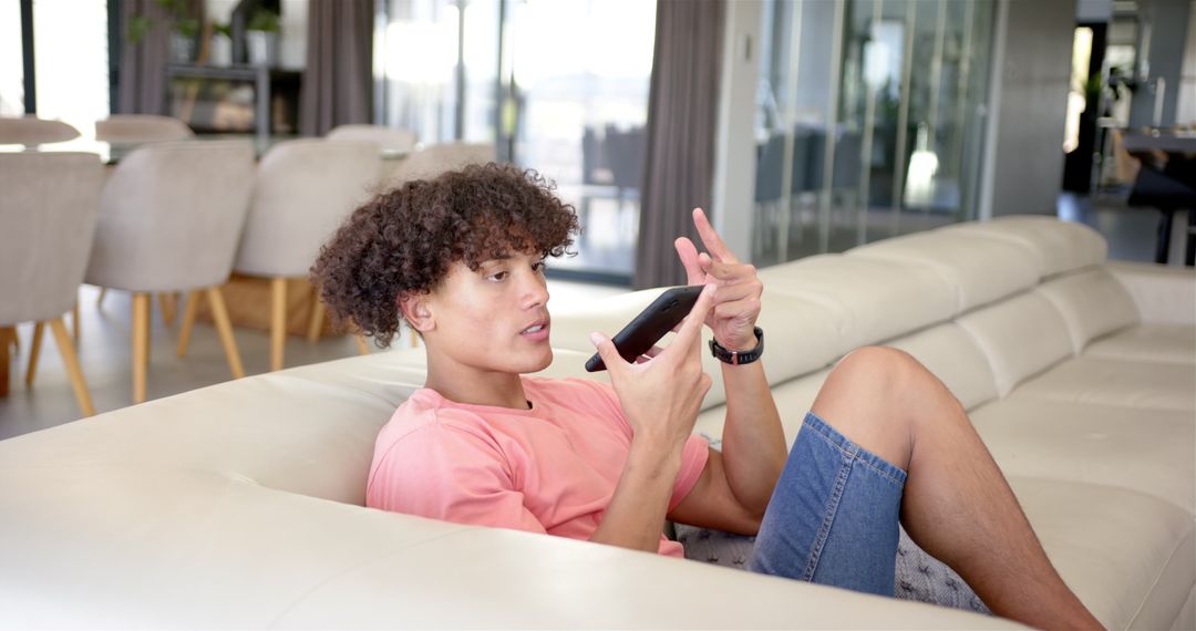 Young Man Relaxing on Couch Using Smartphone