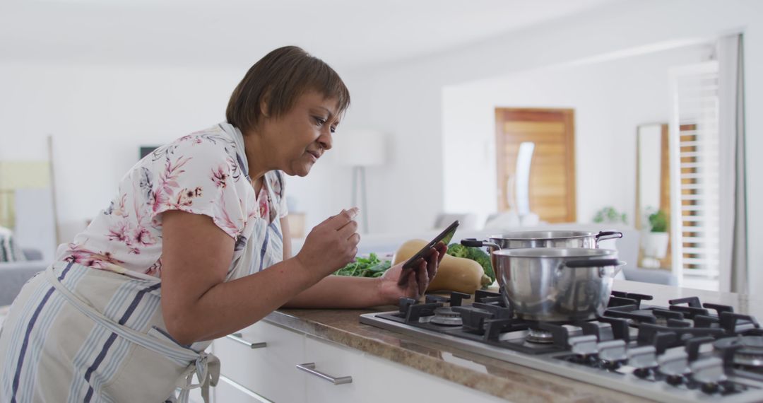 Woman using smartphone in kitchen for cooking - Free Images, Stock Photos and Pictures on Pikwizard.com