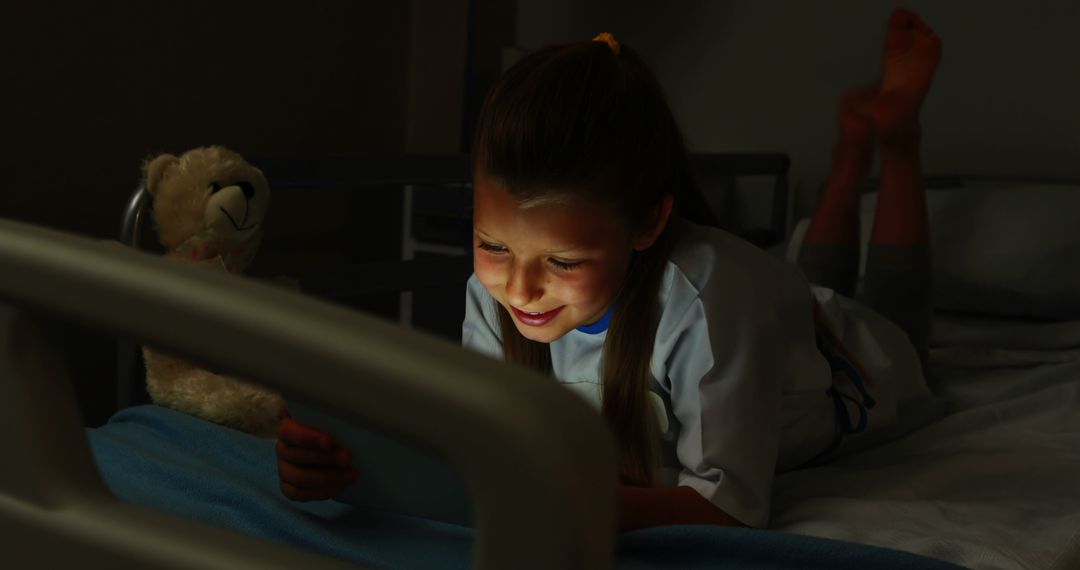 Happy Child Using Tablet in Hospital Bed with Teddy Bear at Night - Free Images, Stock Photos and Pictures on Pikwizard.com