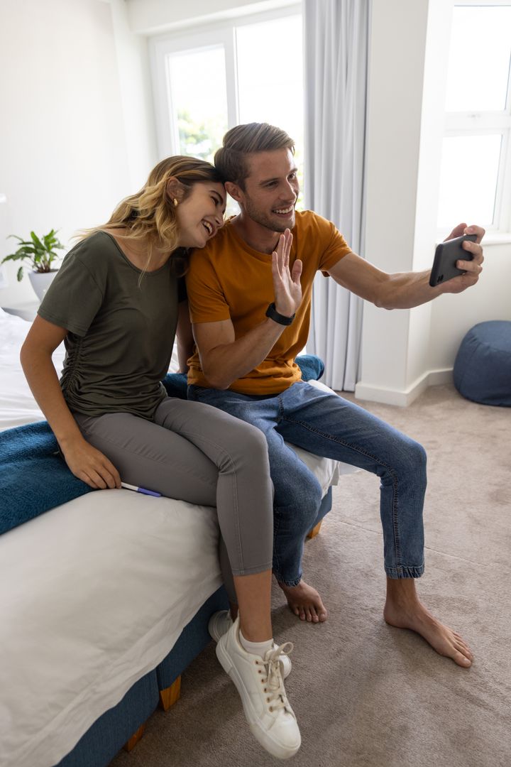 Happy Couple Relaxing Together Enjoying Smartphone in Cozy Bedroom
