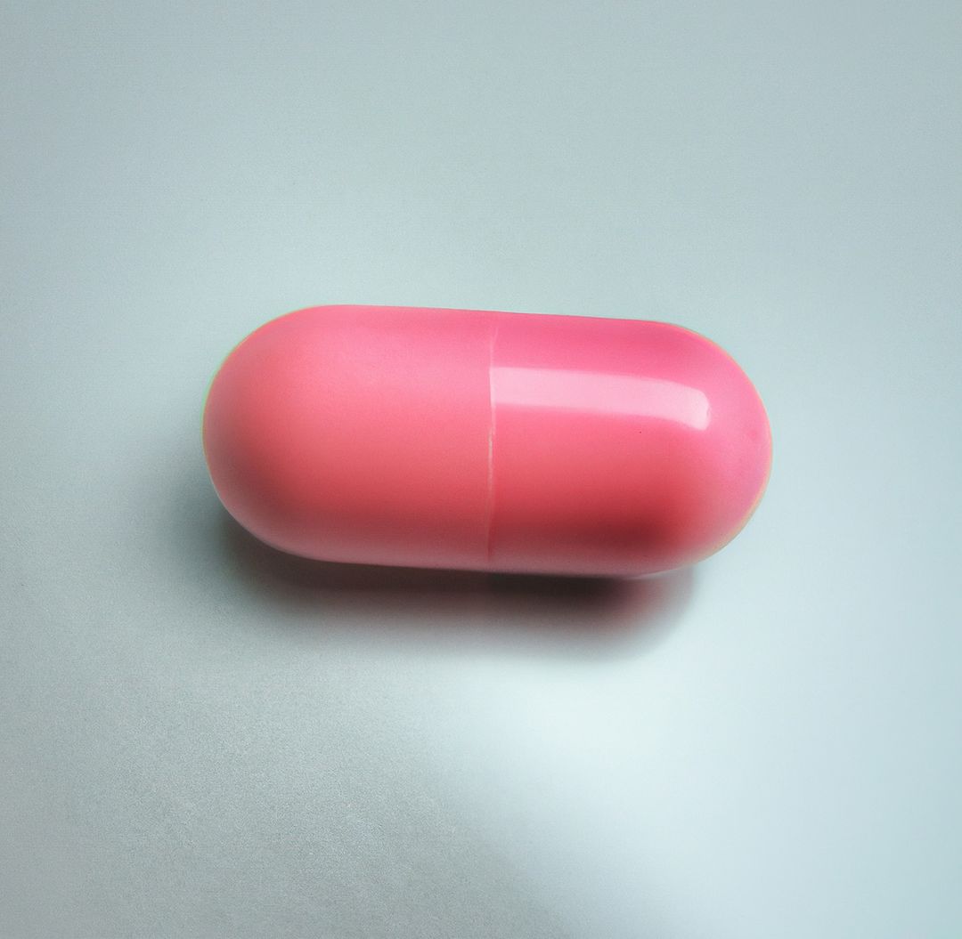 Close up of one pink pill laying on white background - Free Images, Stock Photos and Pictures on Pikwizard.com