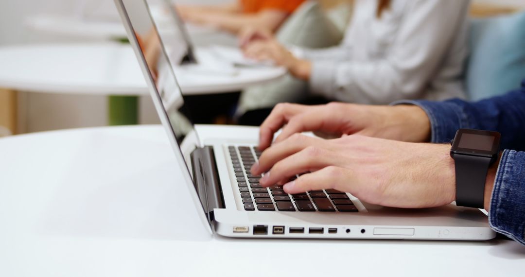 Hands Typing on Laptop in Collaborative Workspace