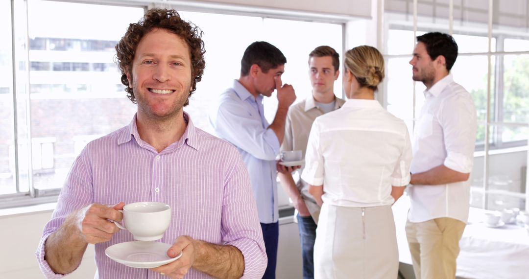 Smiling businessman holding coffee cup in office break room - Free Images, Stock Photos and Pictures on Pikwizard.com