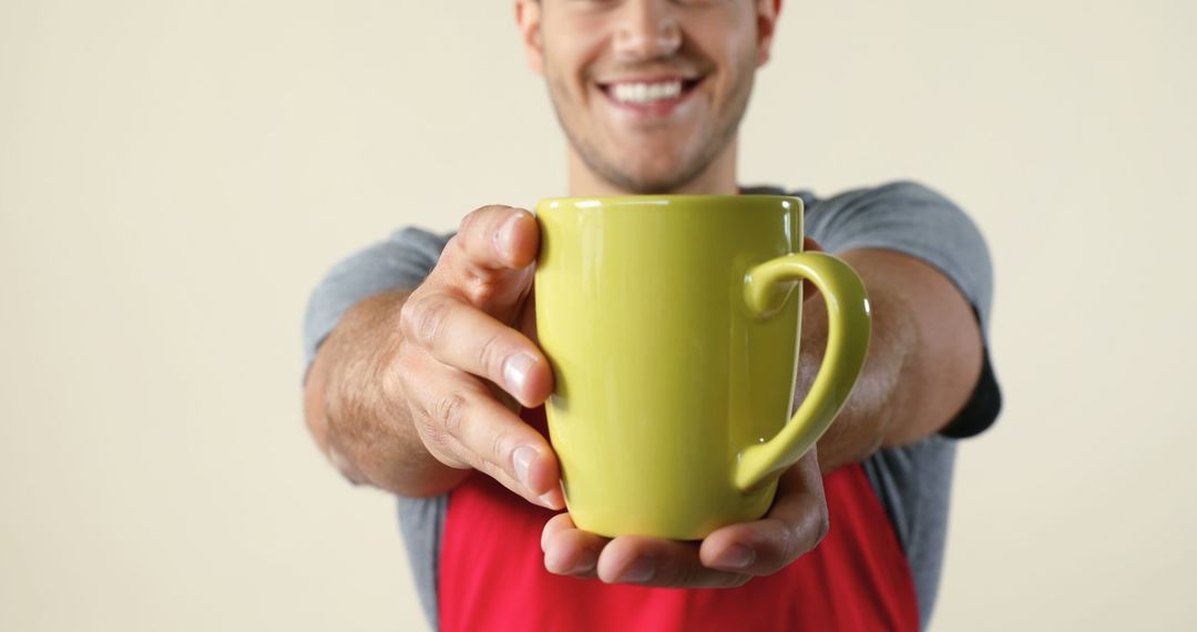 Man Smiling Offering Yellow Mug Close-Up on Simple Background - Free Images, Stock Photos and Pictures on Pikwizard.com