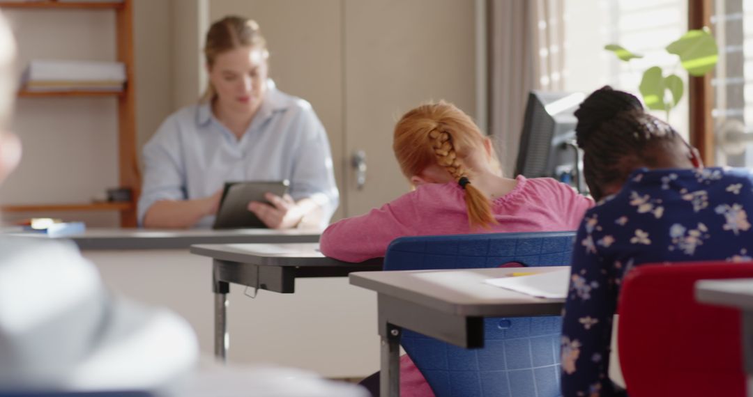 Female Teacher Observes Students Doing Classroom Work
