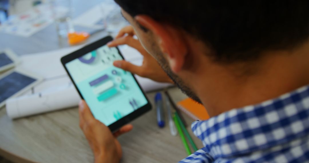 Young Professional Analyzing Data on Tablet in Busy Workspace