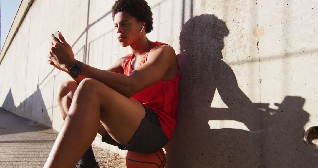 Young Man Lounging with Smartphone and Basketball