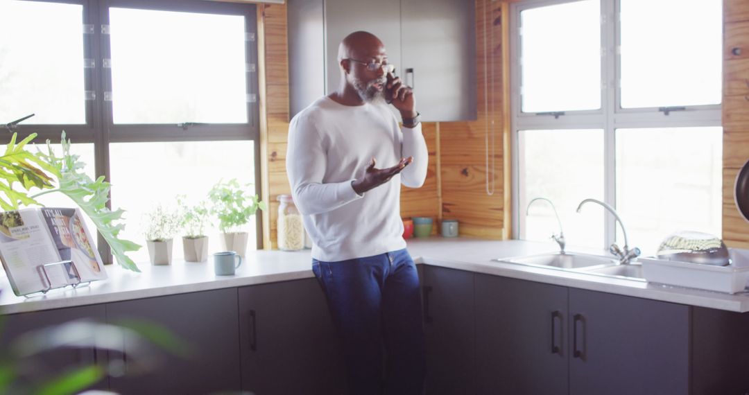 Man Talking on Phone in Modern Kitchen with Natural Light - Free Images, Stock Photos and Pictures on Pikwizard.com