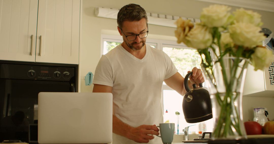 Man Pouring Coffee in Kitchen with Laptop - Free Images, Stock Photos and Pictures on Pikwizard.com