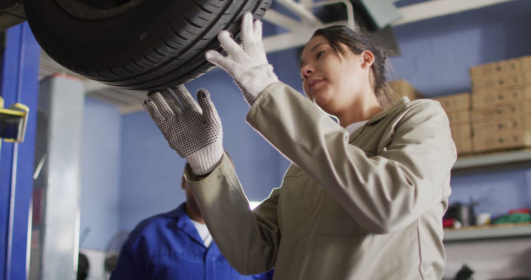 Female Mechanic Wearing Gloves Inspecting Car Tire in Auto Repair Shop - Free Images, Stock Photos and Pictures on Pikwizard.com