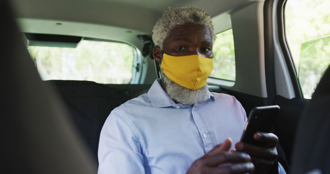 Elderly Man Wearing Yellow Mask Using Smartphone in Car Backseat - Free Images, Stock Photos and Pictures on Pikwizard.com