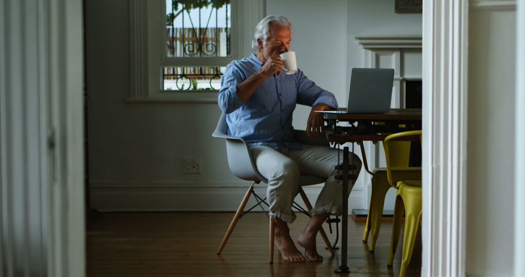 Senior Man Relaxing with Coffee While Using Laptop at Home - Free Images, Stock Photos and Pictures on Pikwizard.com