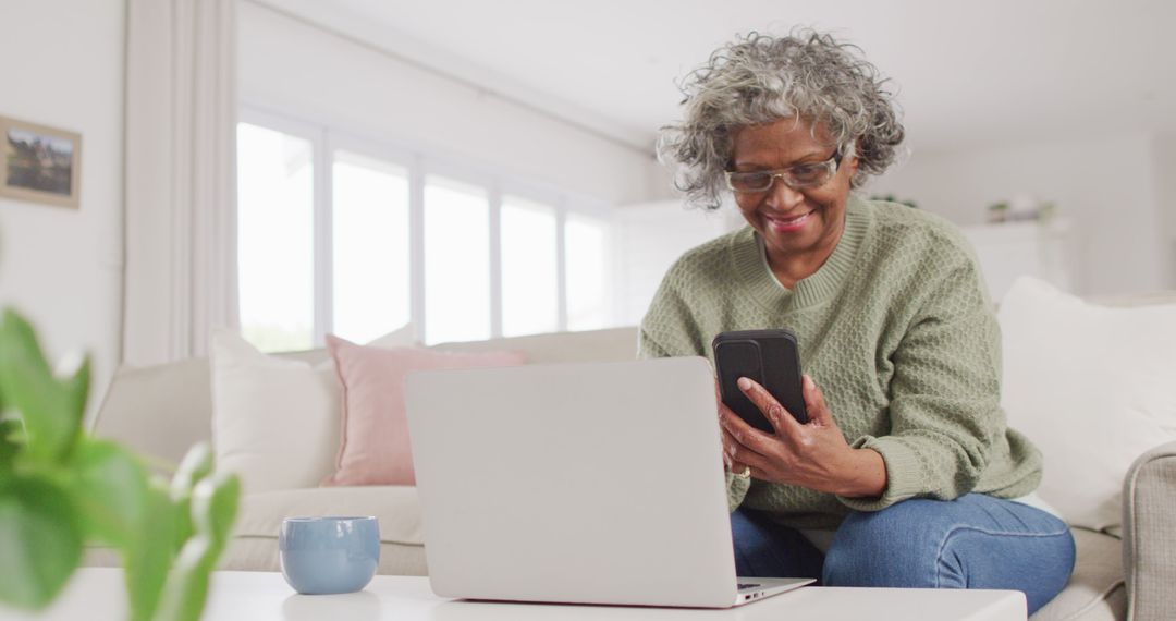 Older Woman Using Laptop and Smartphone in Bright Living Room - Free Images, Stock Photos and Pictures on Pikwizard.com