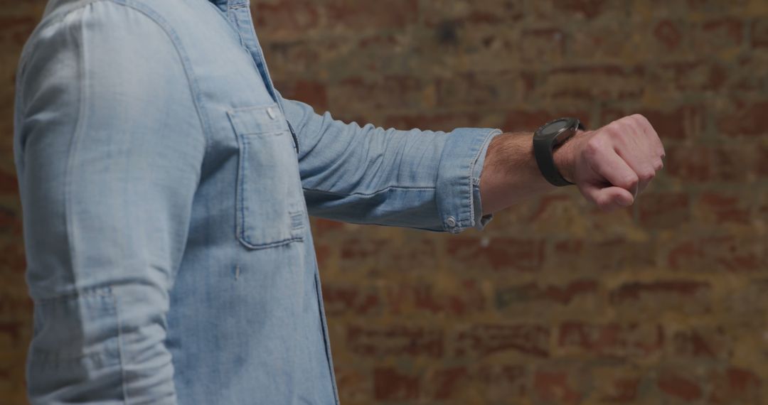 Man Checking Smartwatch Against Brick Wall - Free Images, Stock Photos and Pictures on Pikwizard.com