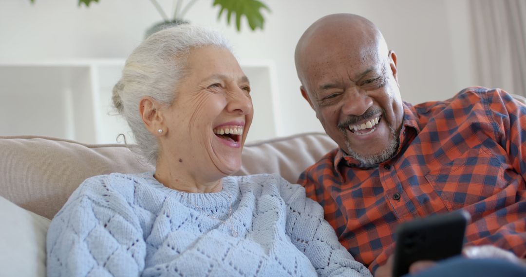 Senior Biracial Couple Enjoying Smartphone Interaction at Home