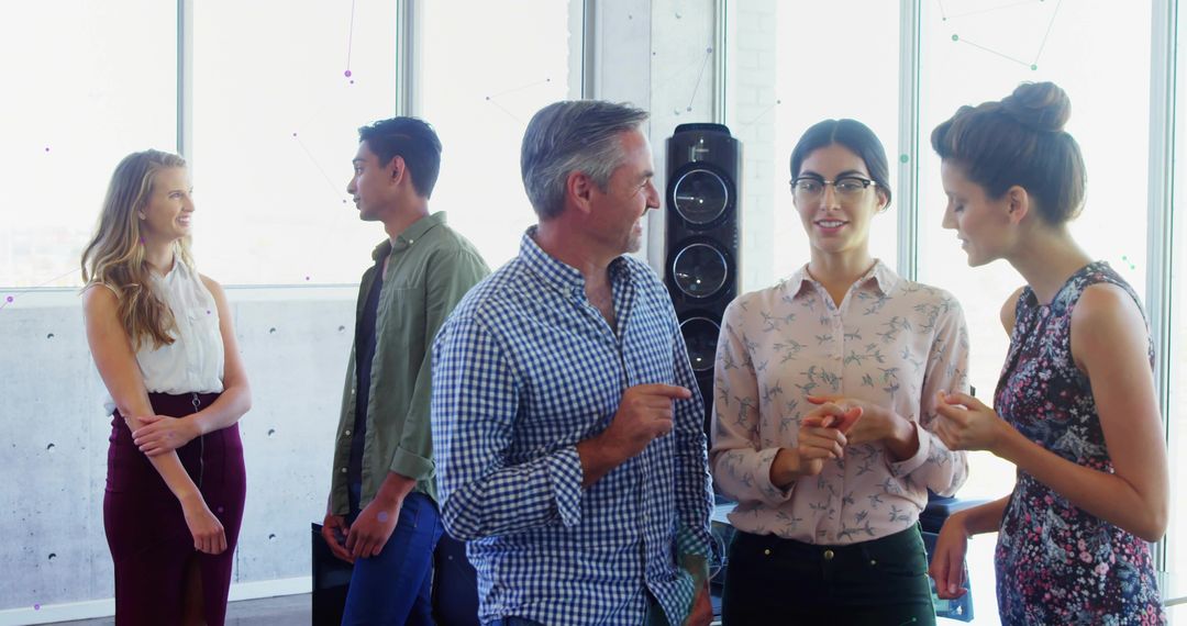 Colleagues Engaging in Workplace Discussion Near Large Windows
