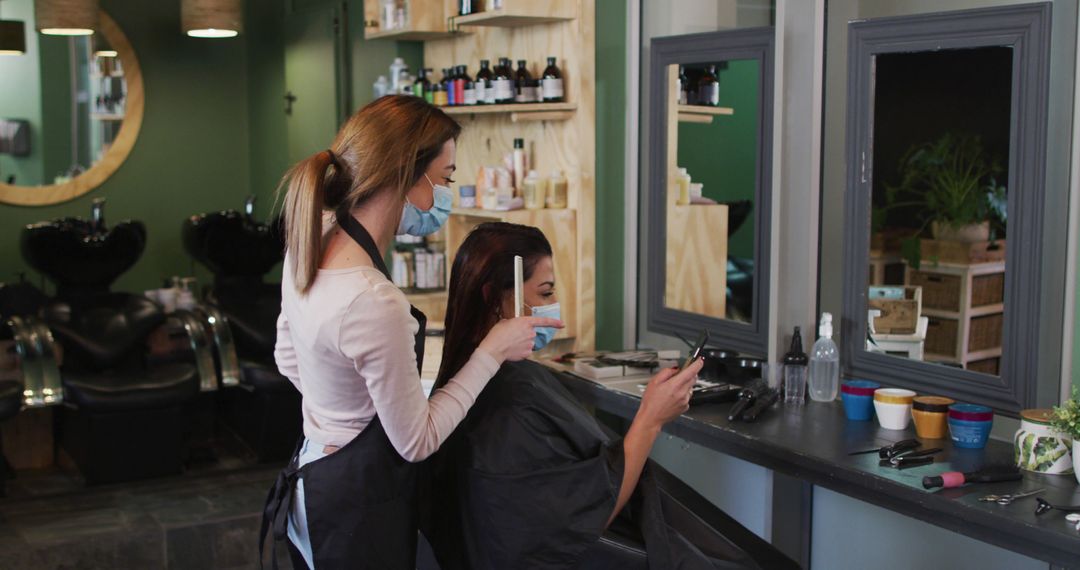 Hairdresser styling woman's hair in modern salon with mask - Free Images, Stock Photos and Pictures on Pikwizard.com