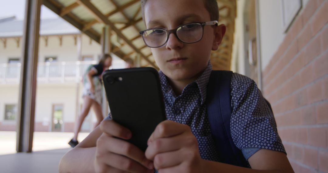 Schoolboy in Glasses Using Smartphone on Playground