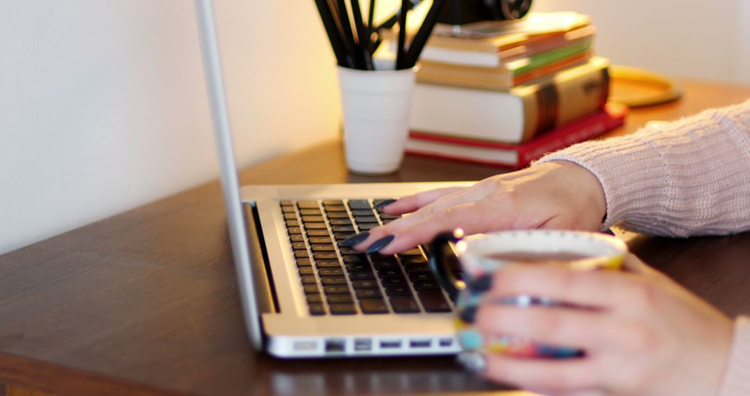 Woman Working on Laptop While Holding Coffee Mug at Desk - Free Images, Stock Photos and Pictures on Pikwizard.com