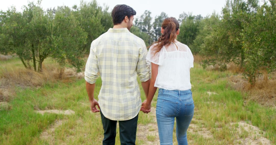 Couple Walking Hand in Hand Through Serene Field