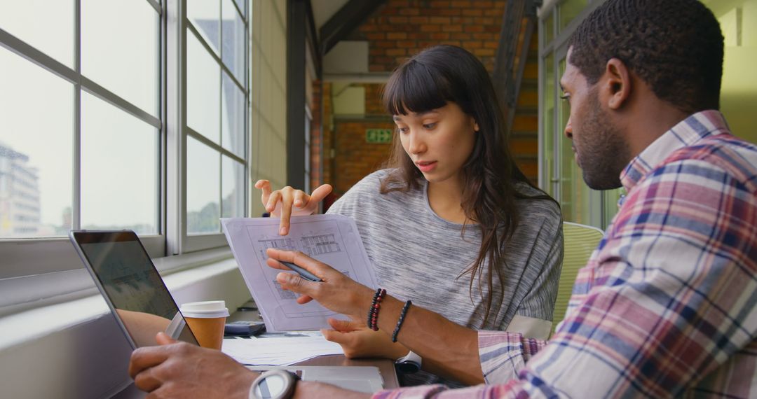 Diverse Colleagues Collaborating on Document in Modern Office