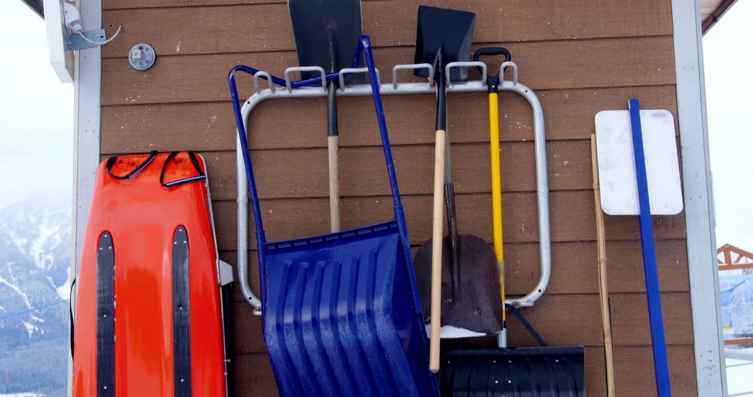 Collection of Snow Shovels and Sleds Hanging on Rustic Wall - Free Images, Stock Photos and Pictures on Pikwizard.com