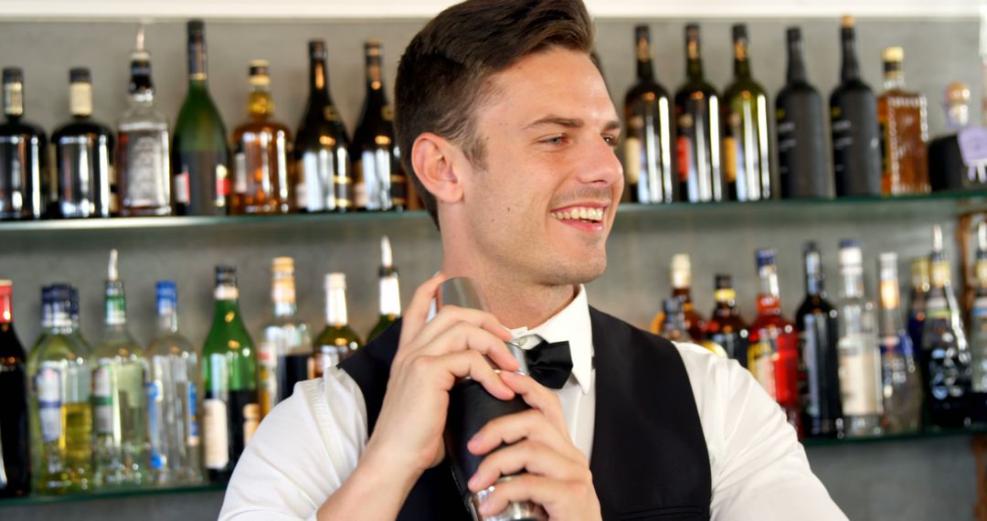 Smiling bartender shaking cocktail mixer behind bar counter - Free Images, Stock Photos and Pictures on Pikwizard.com