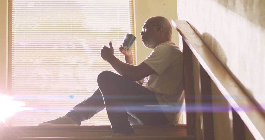 Senior Man Reflecting with Coffee on Staircase in Soft Light
